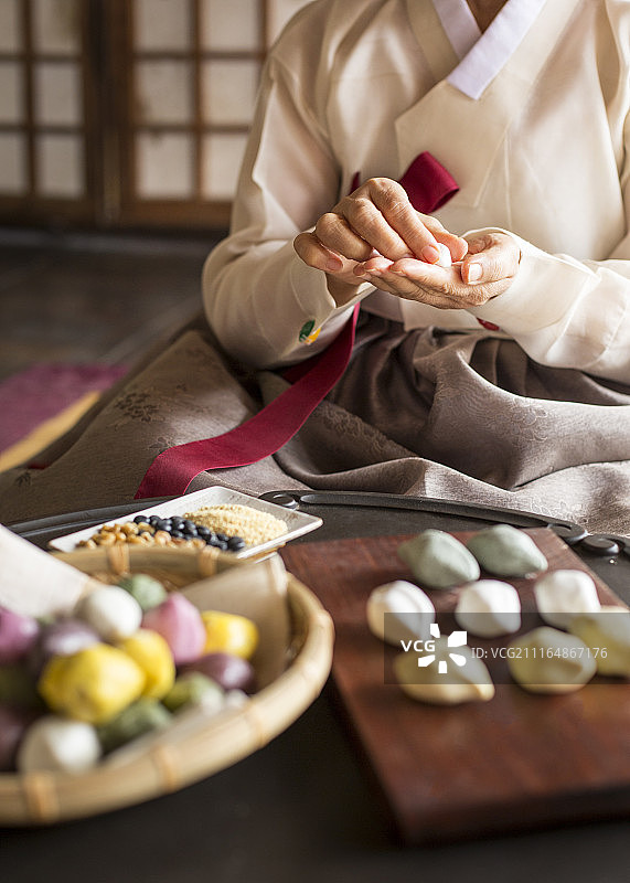 女子身穿韩服在传统韩屋制作松糕图片素材