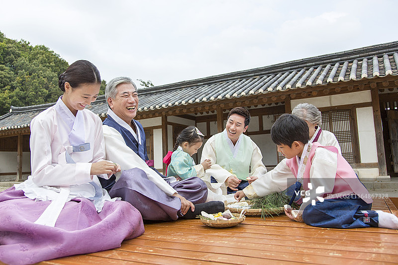 穿着韩服坐在矮木凳上准备过中秋节的三代家庭照片图片素材