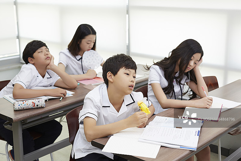 青少年学生在教室里学习感到非常无聊的摄影照片图片素材