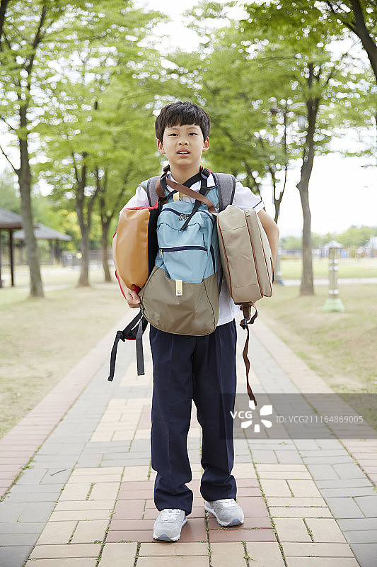 青少年男孩在公园里拿着所有袋子的照片图片素材