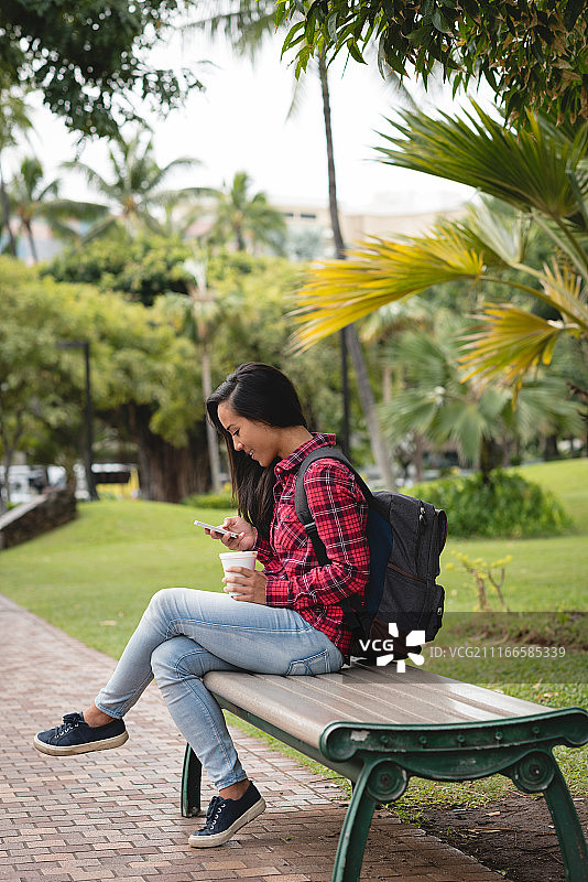 坐在公园长椅上使用手机的女人图片素材