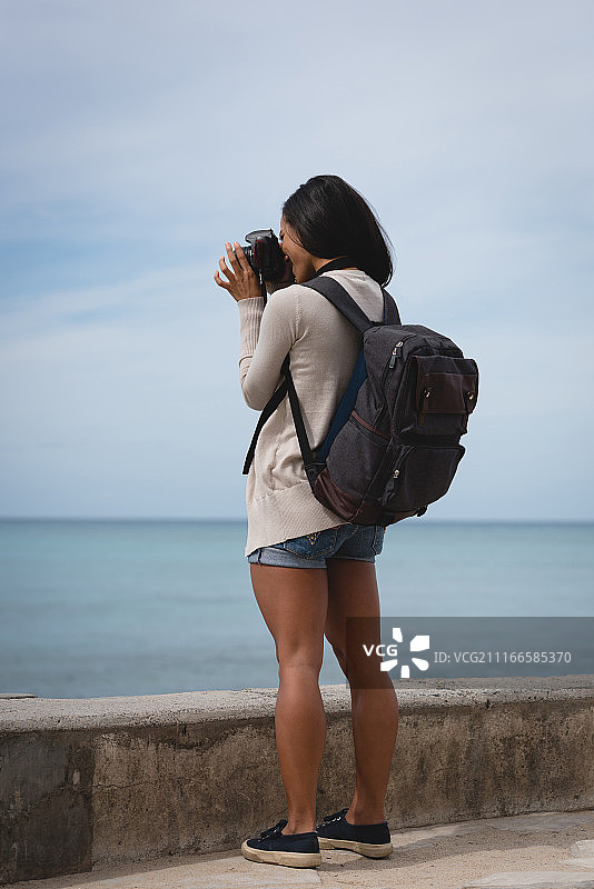 女人用数码相机拍摄大海图片素材