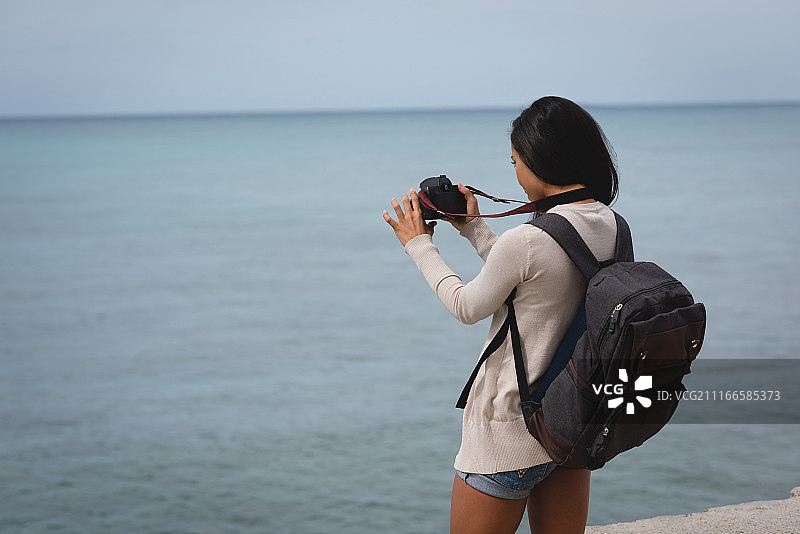 女人在海滩用数码相机拍摄大海图片素材