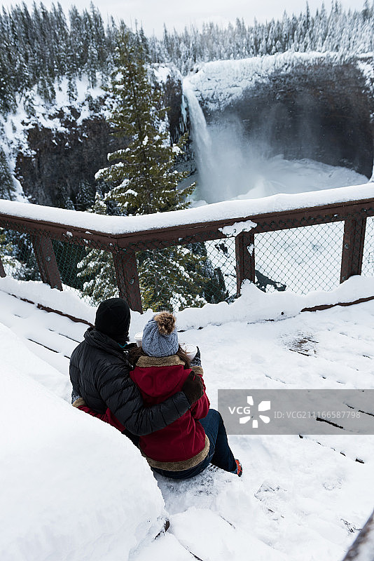 身着保暖服装的情侣观赏瀑布图片素材