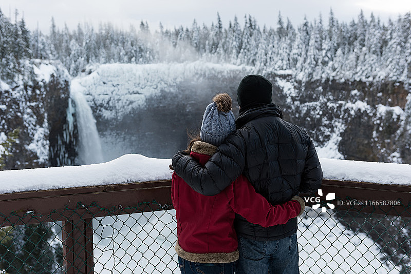 身着保暖服装的情侣观赏瀑布图片素材