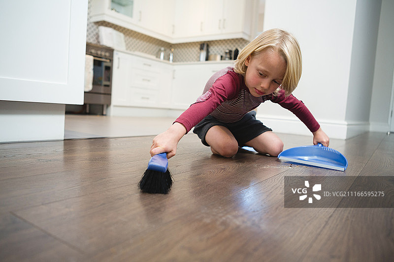 男孩用刷子和簸箕扫灰尘图片素材