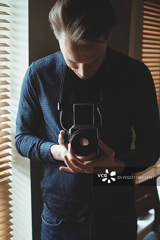 男人在窗边手持老式相机图片素材