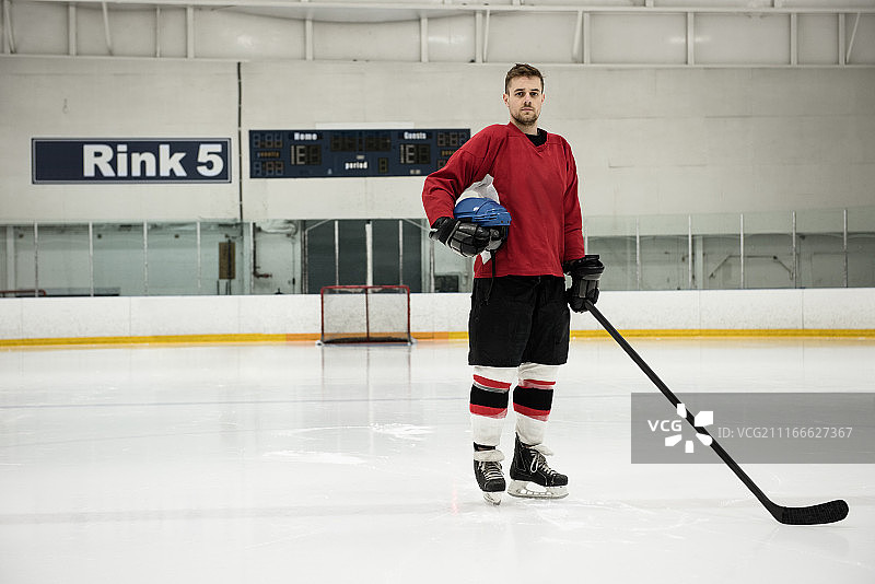 手持头盔和球杆的冰球运动员肖像图片素材