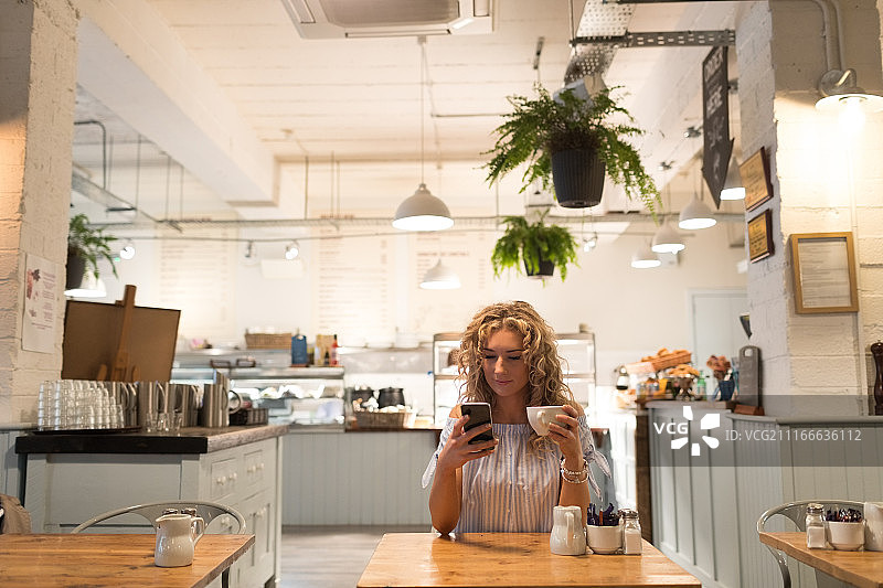 女人手持咖啡杯使用手机图片素材