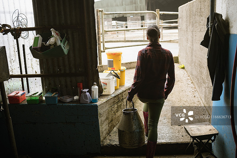 抱着牛奶桶走出谷仓的女人图片素材