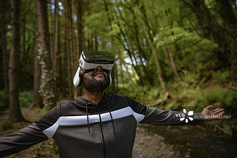 戴VR眼镜，张开双臂的年轻男人图片素材