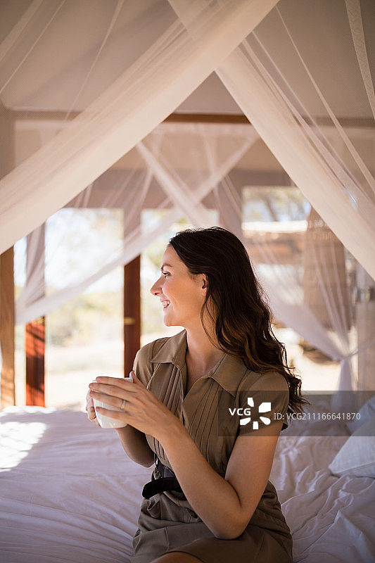 在四柱床上喝咖啡的沉思女人图片素材