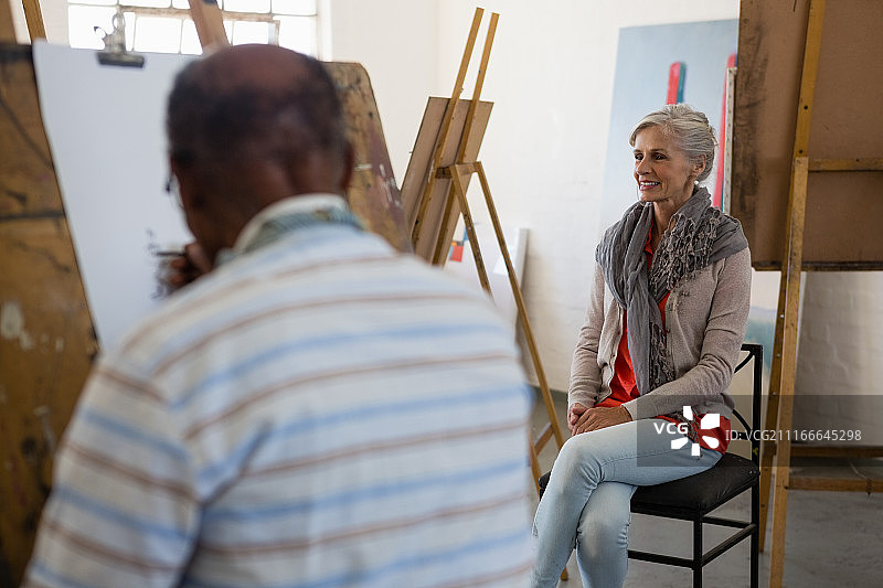 年长的妇女坐在椅子上，艺术家在纸上素描图片素材