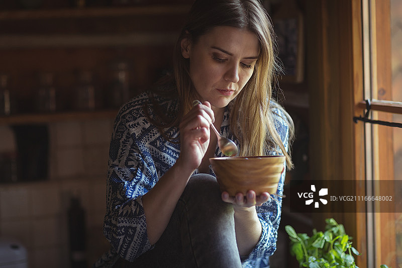 在厨房里吃浆果碗的女人图片素材