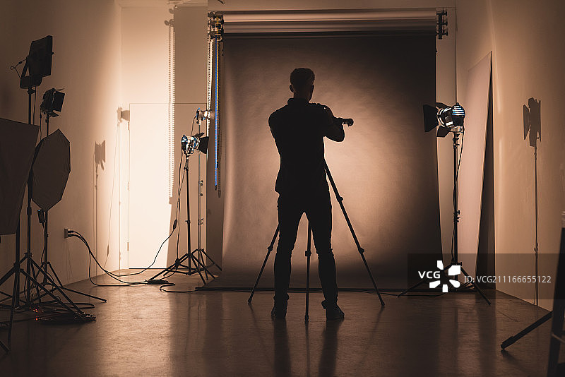 摄影师在背景前调整相机的后视图图片素材