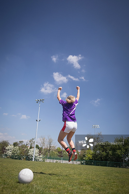 在球场上跳跃的女足球运动员的背影图片素材