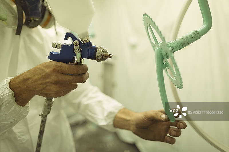 油漆工在车间喷涂自行车齿轮图片素材