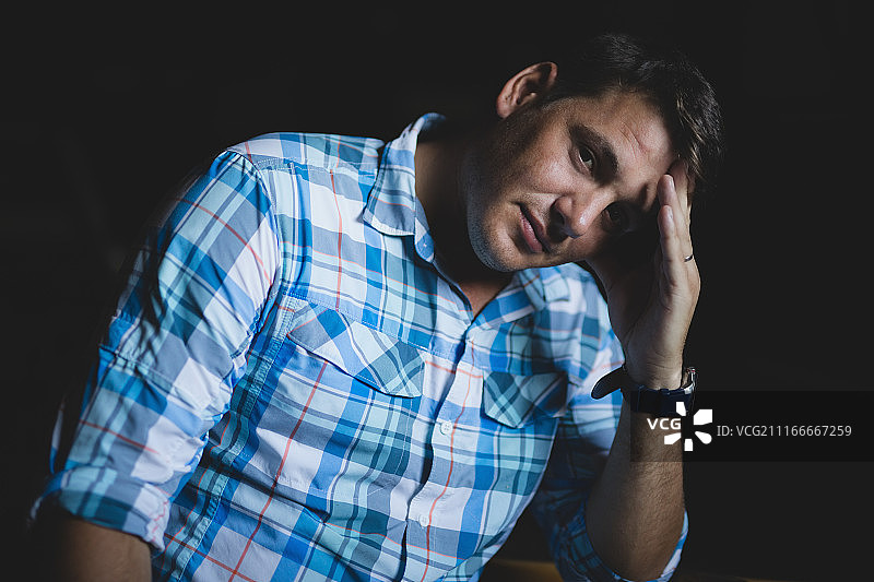 黑色背景下手扶头的男人图片素材