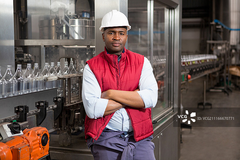 自信的男员工站在果汁工厂的生产线旁图片素材
