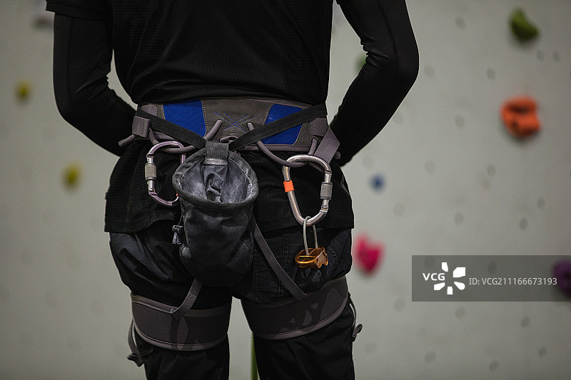 男子站在人造攀岩墙前的腰部特写图片素材