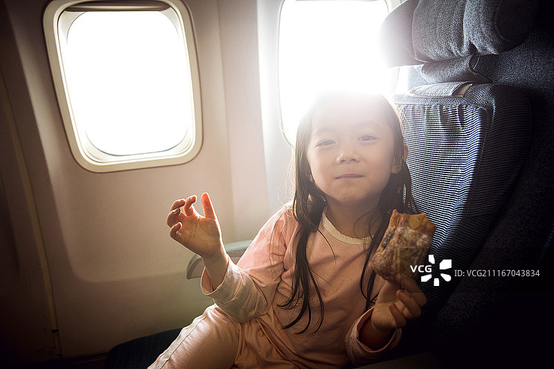 可爱的小女孩在飞机上吃面包图片素材