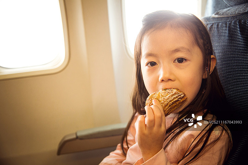 可爱的小女孩在飞机上吃面包图片素材