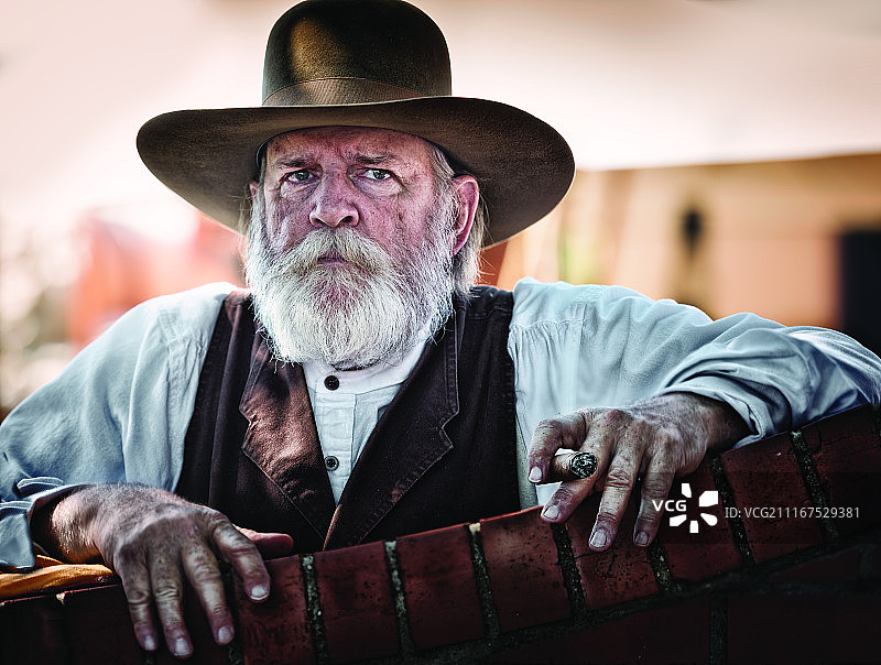 手持雪茄的灰发络腮胡老年牛仔人像图片素材