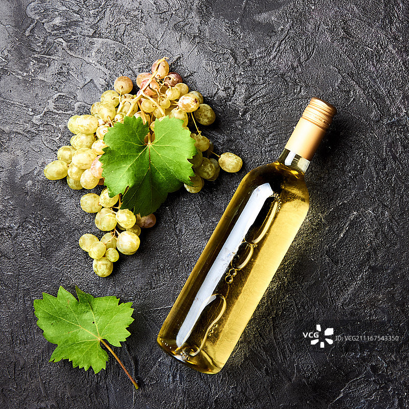 白葡萄酒瓶，葡萄叶，深色背景图片素材