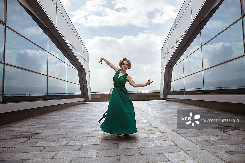 身穿绿色长裙在路面上跳舞的时尚模特图片素材