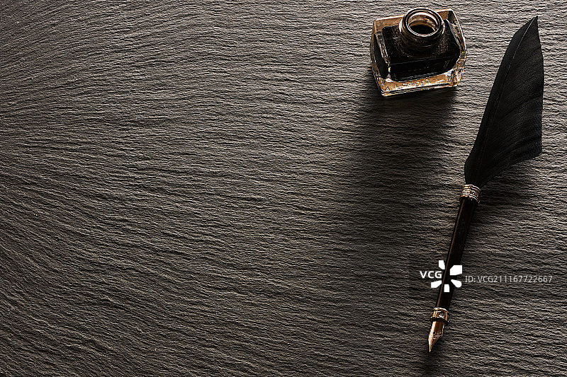 石板背景上的羽毛笔和墨水瓶图片素材