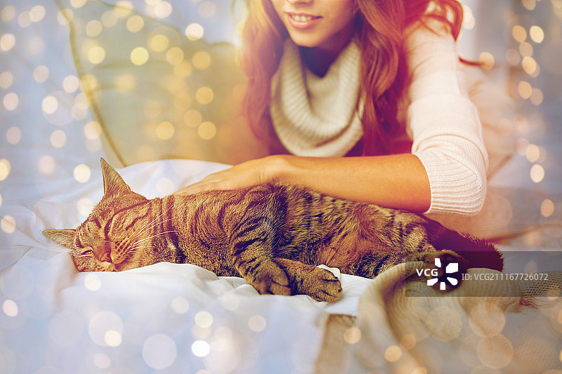 舒适休息：年轻女子与猫咪在家中床上图片素材