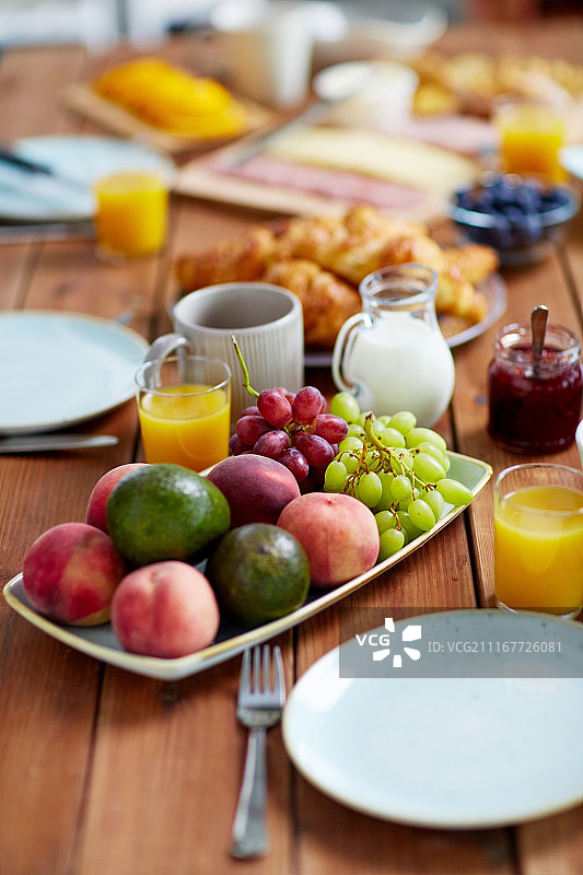 美食与饮食概念：早餐时木桌上放着一盘水果、橙汁、牛奶和果酱图片素材