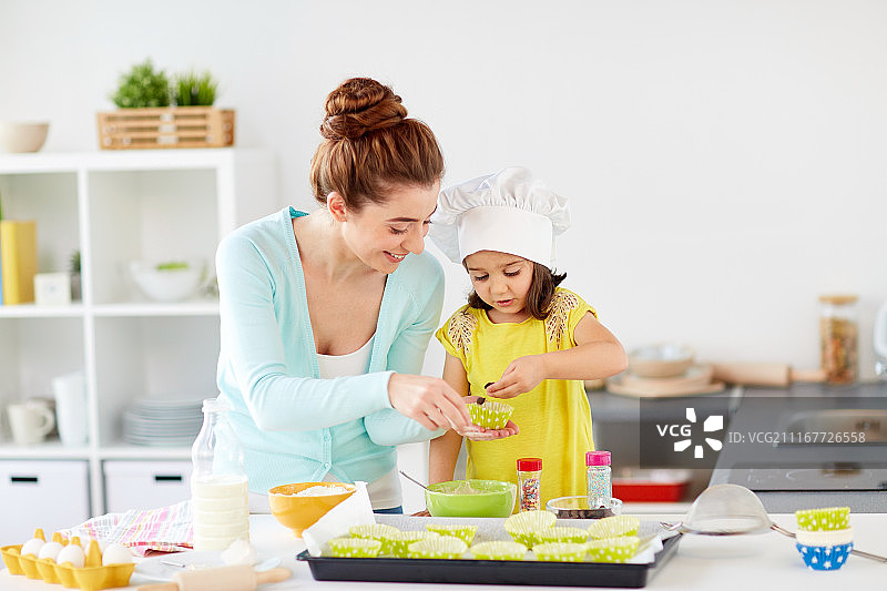 家庭烹饪：快乐的母女在厨房做纸杯蛋糕图片素材