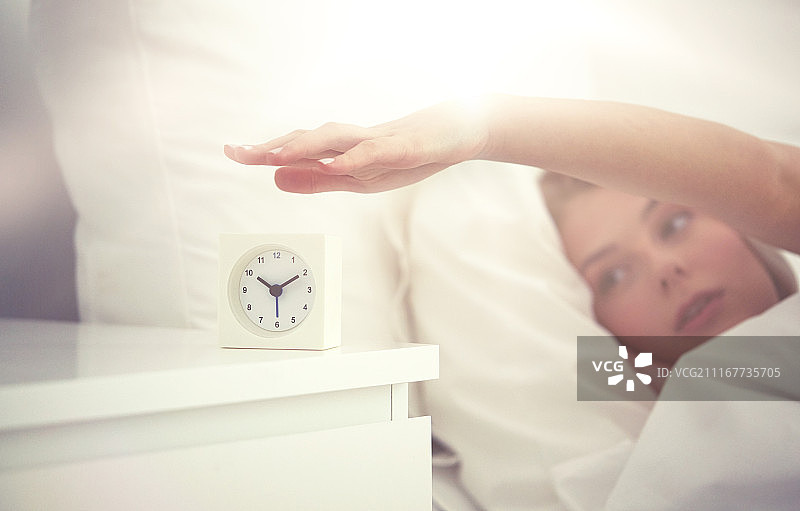 休息、睡眠：年轻女子在家中卧室关闭闹钟图片素材