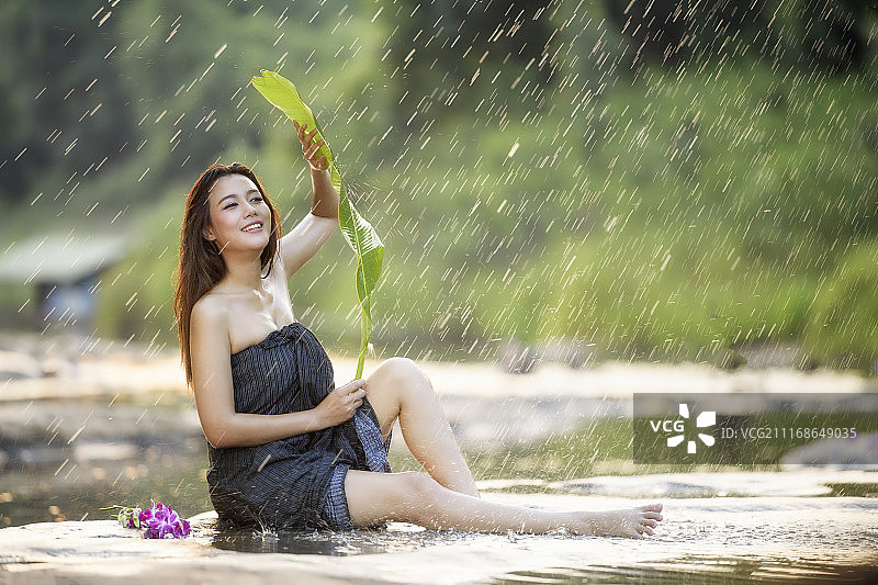 女人用树叶保护自己免受雨淋图片素材