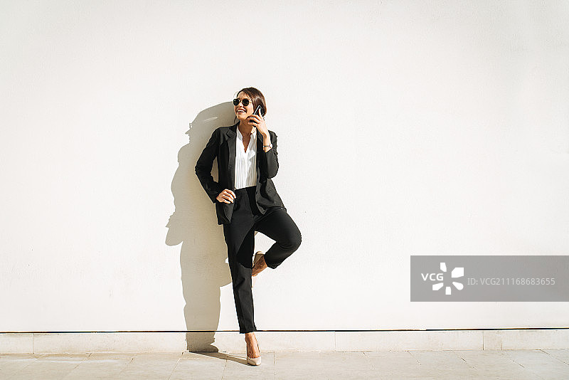 靠墙用手机交谈的女商人图片素材
