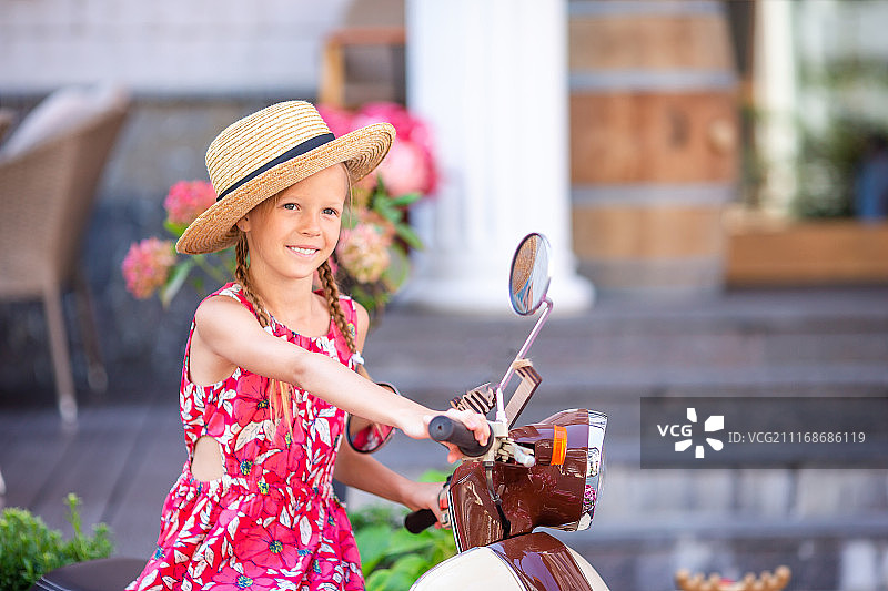 戴着帽子骑着轻便摩托车的可爱小女孩图片素材