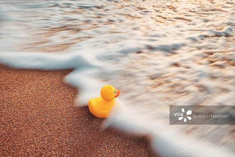 漂浮在水中的黄色橡皮鸭玩具，沙滩上的日出图片素材