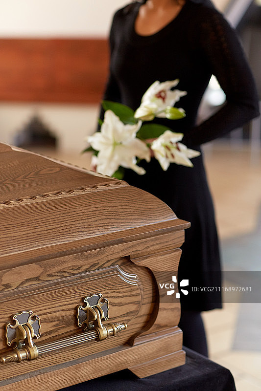 人物与哀悼概念-葬礼上拿着鲜花和棺材的女人图片素材