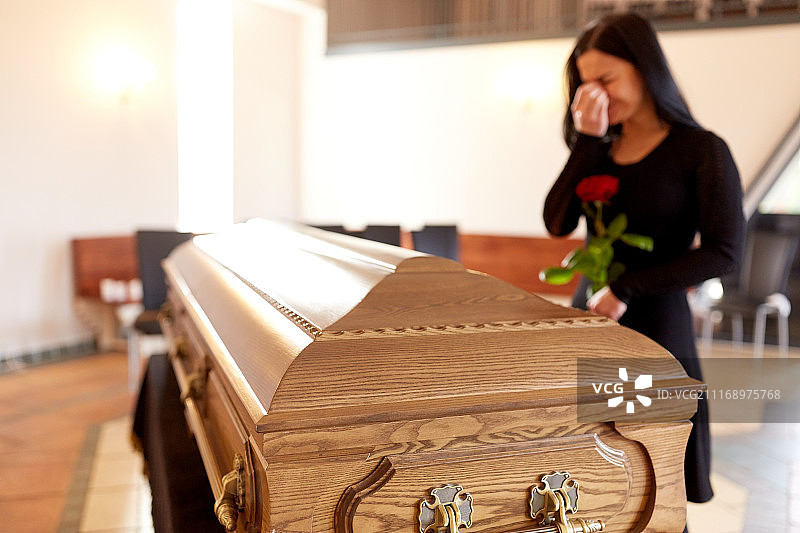 哀悼概念：在教堂葬礼上抱着棺材哭泣的妇女图片素材