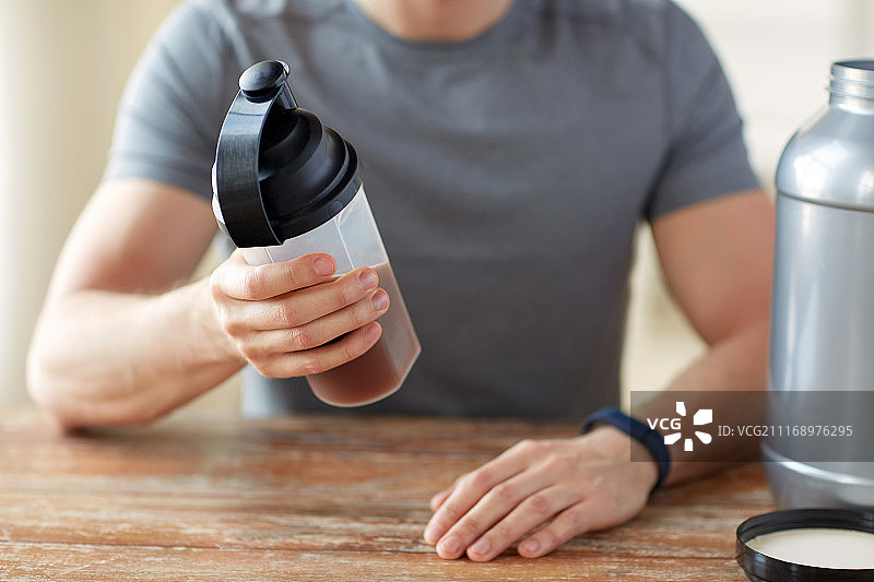 运动健康生活方式概念：男子佩戴运动追踪器，准备蛋白奶昔图片素材