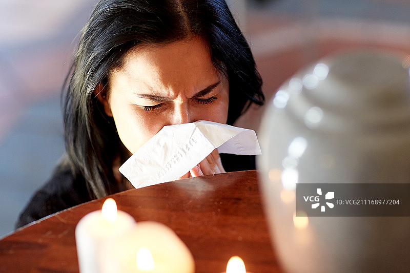 葬礼上的哀悼：在教堂里用骨灰瓮哭泣的女人图片素材