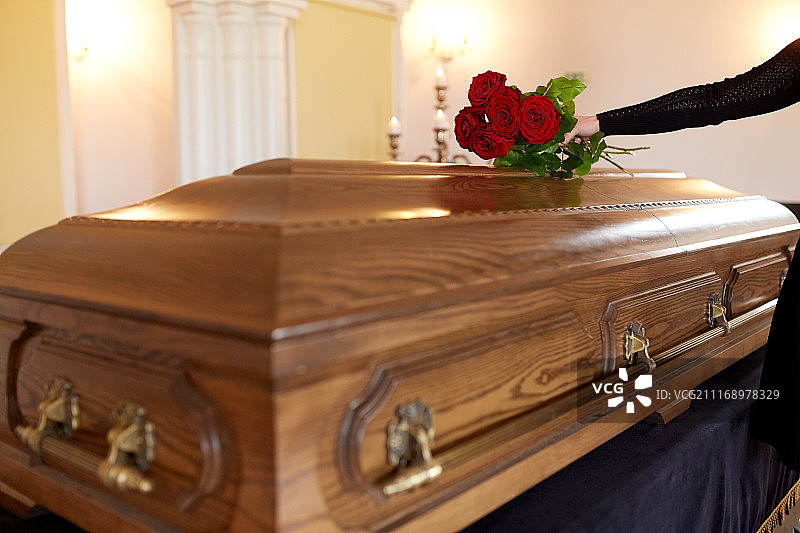 葬礼概念：拿着红玫瑰的女人和棺材图片素材
