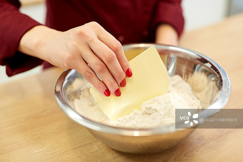 烹饪食物：厨师用铲子搅拌碗里的面粉，制作面糊或面团图片素材