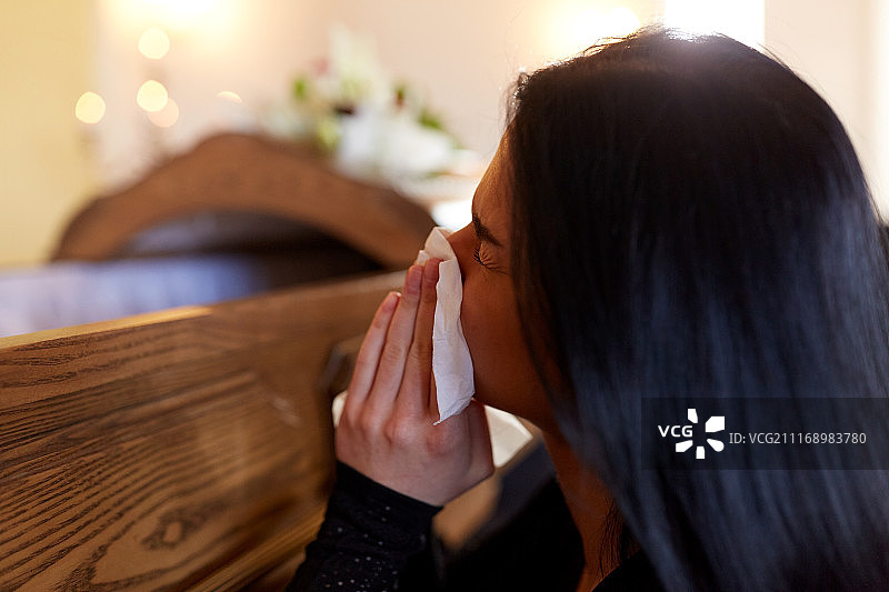 哀悼概念：在教堂葬礼上抱着棺材哭泣的妇女图片素材