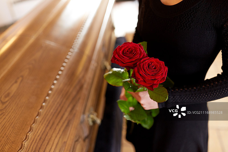 葬礼概念：拿着红玫瑰的女人和棺材图片素材