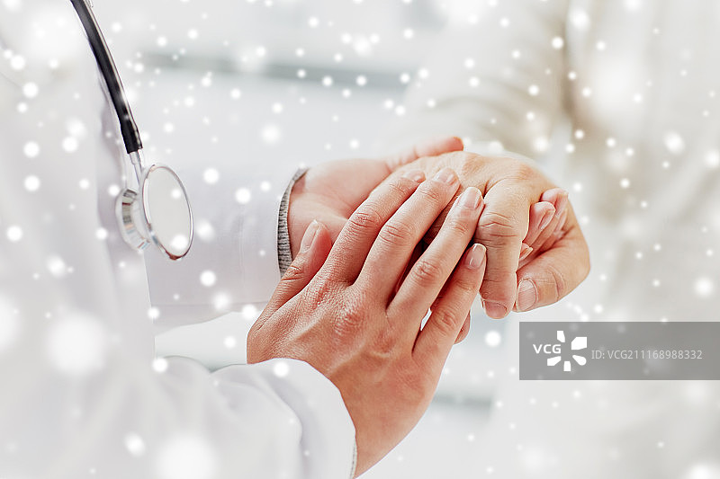 医药、年龄、支持、医疗保健和人物概念——医生或护士在医院握着老年男人的手部的特写，雪景背景图片素材