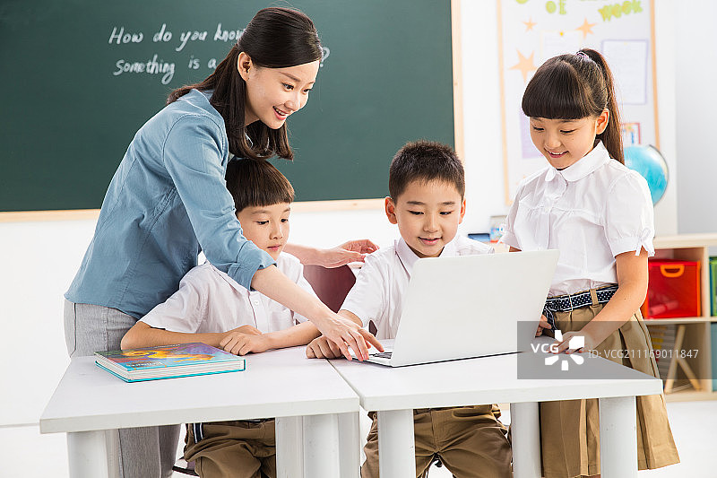 教师和小学生在教室里使用电脑图片素材