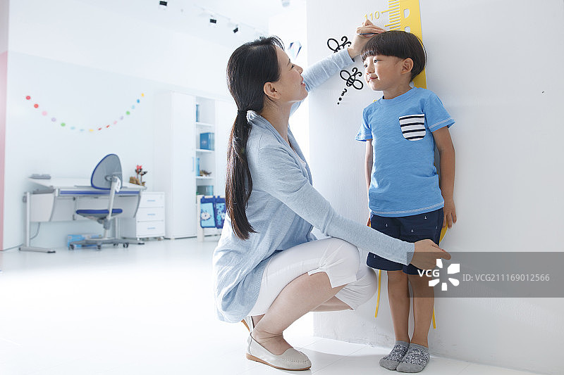 妈妈在为小男孩测量身高图片素材