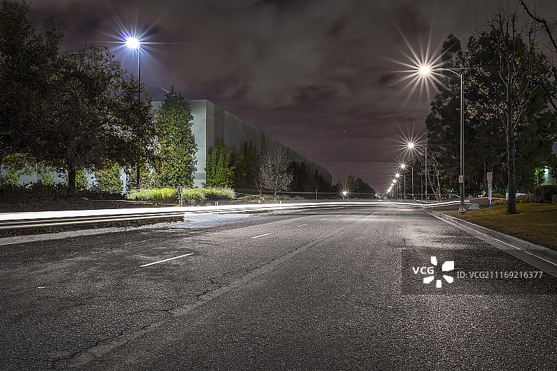 夜晚的绿树成荫的道路，路灯和美国圣菲斯普林斯的现代化仓库图片素材